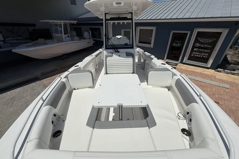 Slide: The Image of 2026 Edgewater 250CC boat interior with white seating and table, docked near a blue building. - 17