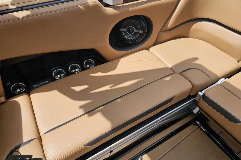 Slide: The Image of 2022 Supra SE 550 boat interior with tan leather seating and built-in speakers. - 104
