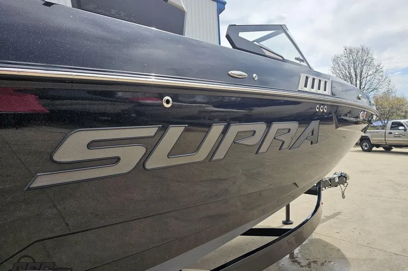 Slide: The Image of 2022 Supra SE 550 boat with sleek design and bold branding in a parking area. - 13