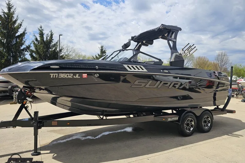 Slide: The Image of 2022 Supra SE 550 boat on trailer, sleek black design, parked outdoors. - 22