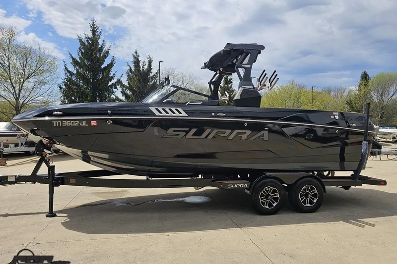 Slide: The Image of 2022 Supra SE 550 boat on trailer, sleek black design, parked outdoors. - 23