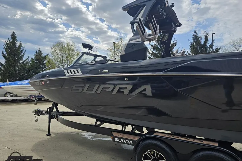 Slide: The Image of 2022 Supra SE 550 boat on trailer, parked outdoors under cloudy sky. - 27