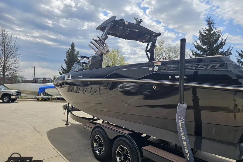 Slide: The Image of 2022 Supra SE 550 boat on trailer under cloudy sky. - 28