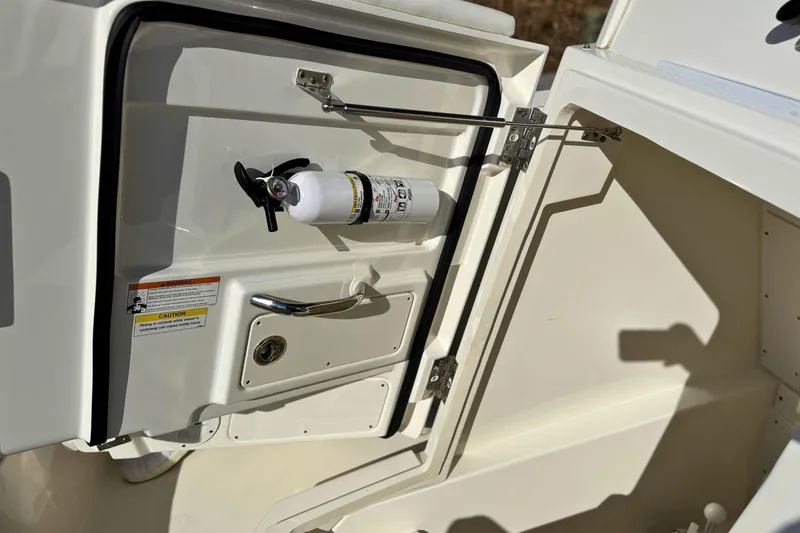 Slide: The Image of 2021 Pursuit S 268 Sport boat storage compartment with fire extinguisher and safety labels. - 16