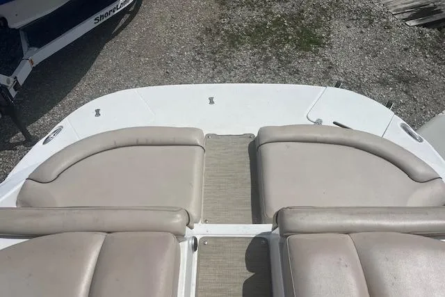 Slide: The Image of 2015 Rinker 276 Captiva Cuddy boat with beige seating on a gravel surface. - 10