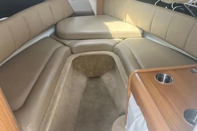 Slide: The Image of 2015 Rinker 276 Captiva Cuddy interior with beige seating and wooden accents. - 14