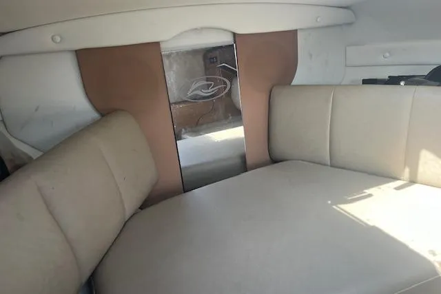 Slide: The Image of 2015 Rinker 276 Captiva Cuddy cabin interior with beige seating and storage space. - 15