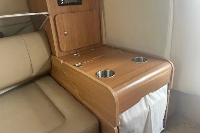 Slide: The Image of 2015 Rinker 276 Captiva Cuddy interior with wooden cabinetry and cup holders. - 16