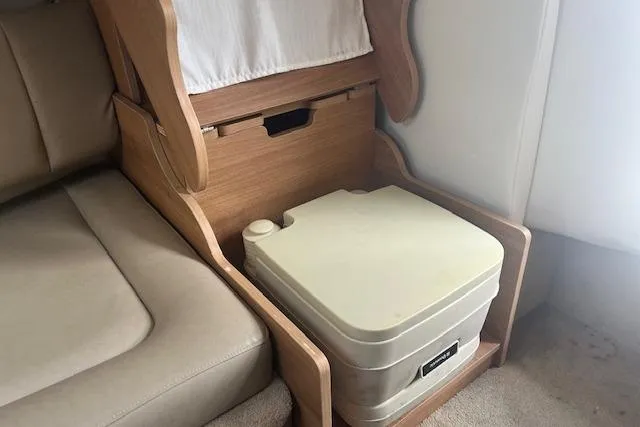 Slide: The Image of 2015 Rinker 276 Captiva Cuddy interior with portable toilet and wooden cabinetry. - 17