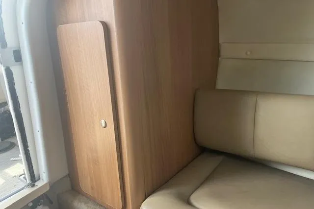 Slide: The Image of 2015 Rinker 276 Captiva Cuddy interior with beige seating and wooden cabinet. - 18