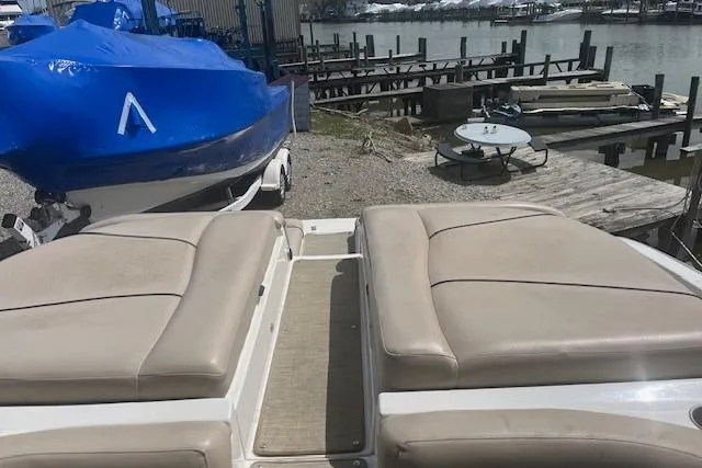 Slide: The Image of 2015 Rinker 276 Captiva Cuddy boat docked, featuring beige seating and nearby covered vessel. - 9