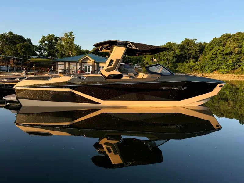 The Image of 2025 Nautique Super Air Nautique G25 Paragon boat on calm water, surrounded by trees. - 0