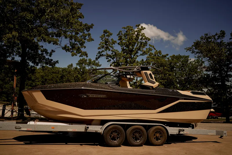Slide: The Image of 2025 Nautique Super Air Nautique G25 Paragon boat on trailer, surrounded by trees. - 4