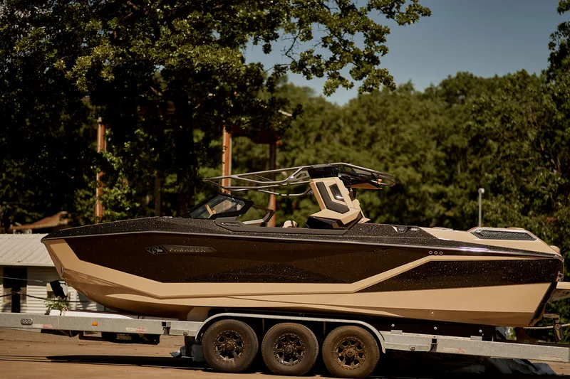 Slide: The Image of 2025 Nautique Super Air Nautique G25 Paragon on trailer, surrounded by trees. - 6