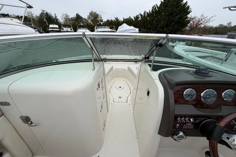 Slide: The Image of 2009 Sea Ray 210 Sundeck interior with dashboard and seating area, wet from rain. - 11