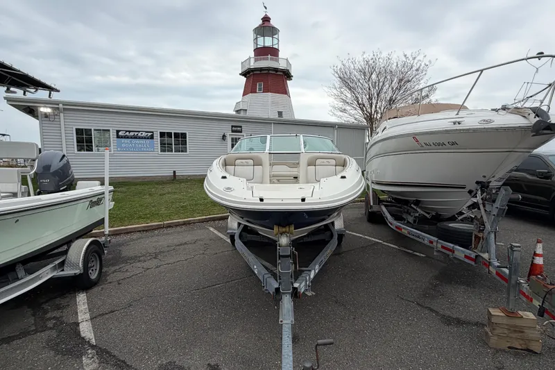 Slide: The Image of 2009 Sea Ray 210 Sundeck boat on trailer, parked near a lighthouse and sales building. - 4