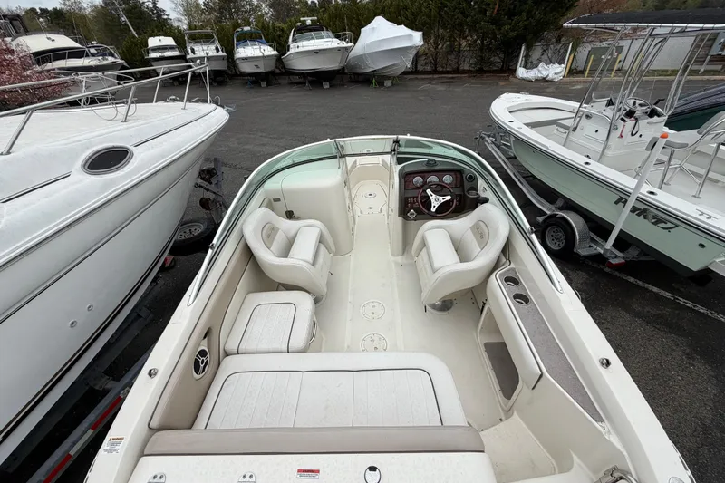 Slide: The Image of 2009 Sea Ray 210 Sundeck boat interior with seating and steering wheel, parked among other boats. - 6