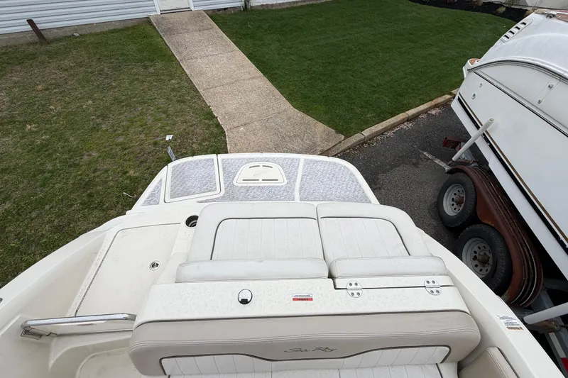 Slide: The Image of 2009 Sea Ray 210 Sundeck boat with cushioned seating, parked on a trailer. - 7