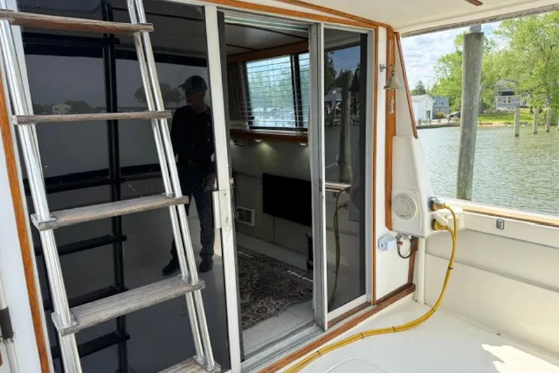 Slide: The Image of 1978 Mainship 34 Trawler interior view with sliding door and ladder, docked by the water. - 13