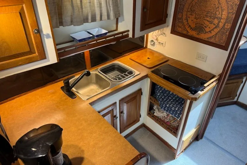 Slide: The Image of 1978 Mainship 34 Trawler kitchen with sink, stove, and wooden cabinetry. - 16