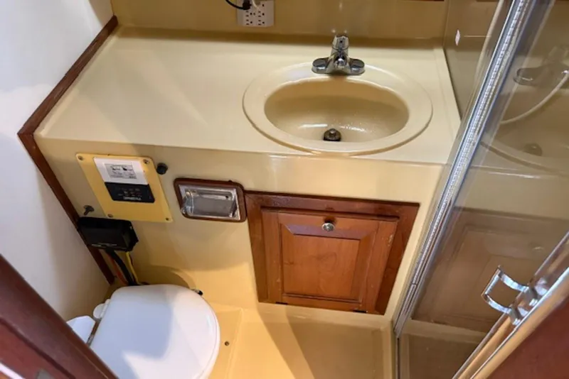 Slide: The Image of 1978 Mainship 34 Trawler bathroom with sink, toilet, and wooden cabinetry. - 21