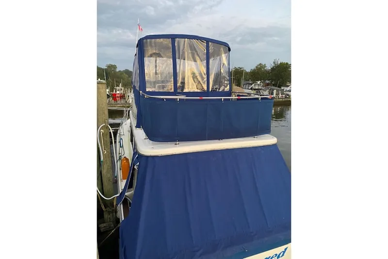 Slide: The Image of 1978 Mainship 34 Trawler with blue canvas cover docked at marina. - 5