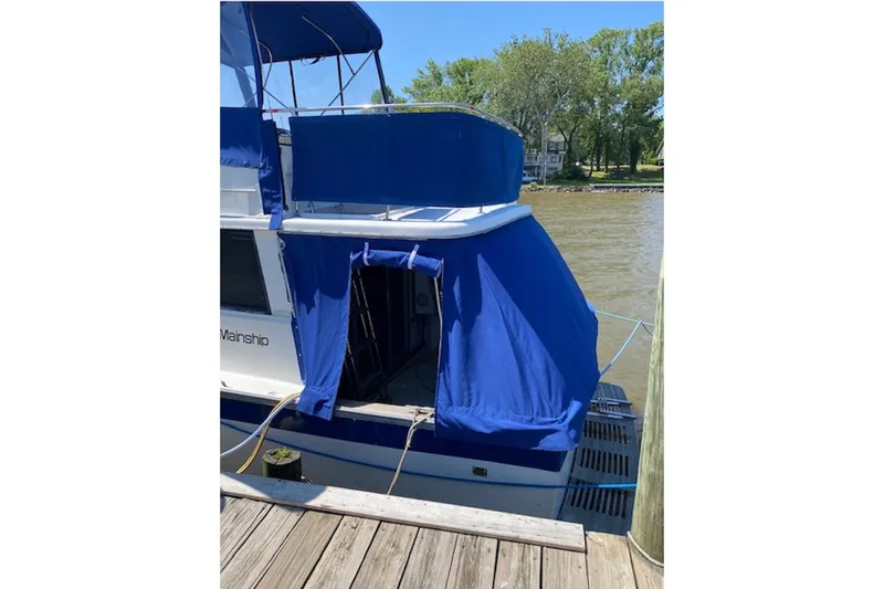 Slide: The Image of 1978 Mainship 34 Trawler docked, featuring blue canvas covers and wooden pier. - 6