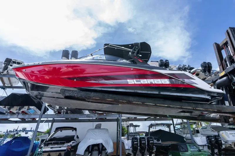 Slide: The Image of 2017 Scarab 255 H.O. Impulse boat in storage, vibrant red hull, clear sky background. - 5