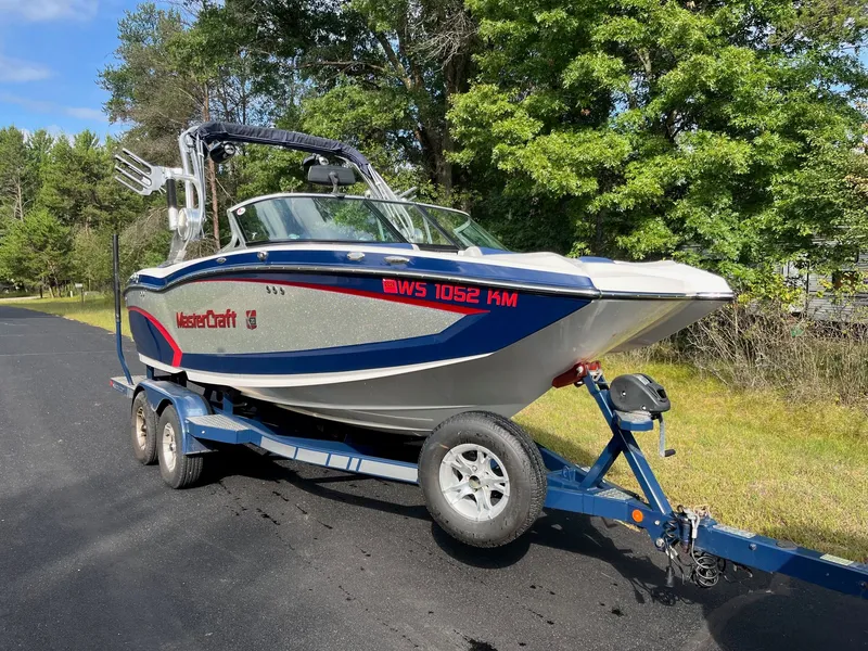 Slide: The Image of 2015 MasterCraft X20 boat on trailer, surrounded by trees. - 4