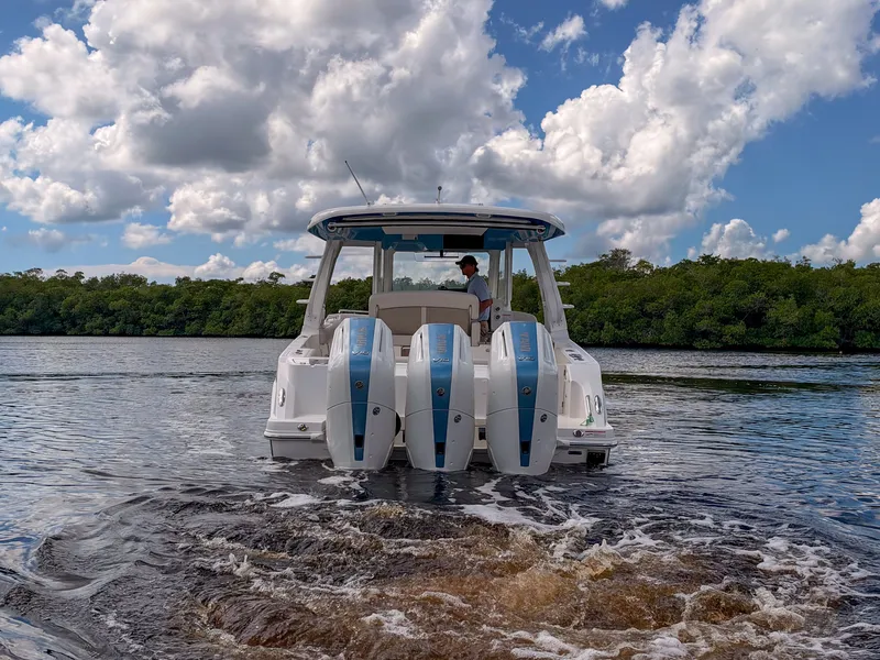 Slide: The Image of A 2027 Boston Whaler 350 Realm cruising on a calm river under a cloudy sky. - 44