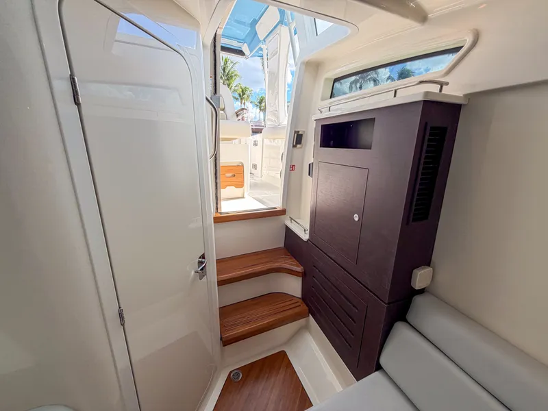 Slide: The Image of Interior of the Boston Whaler 350 Realm with wooden steps, seating area, and cabinet. - 37