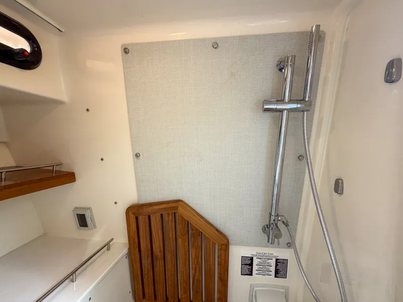 Slide: The Image of The shower area of a 2027 Boston Whaler 350 Realm with a wooden seat and showerhead. - 36