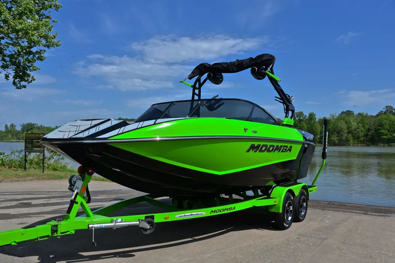 Slide: The Image of 2024 Moomba Mondo boat in vibrant green on trailer by a lakeside. - 10