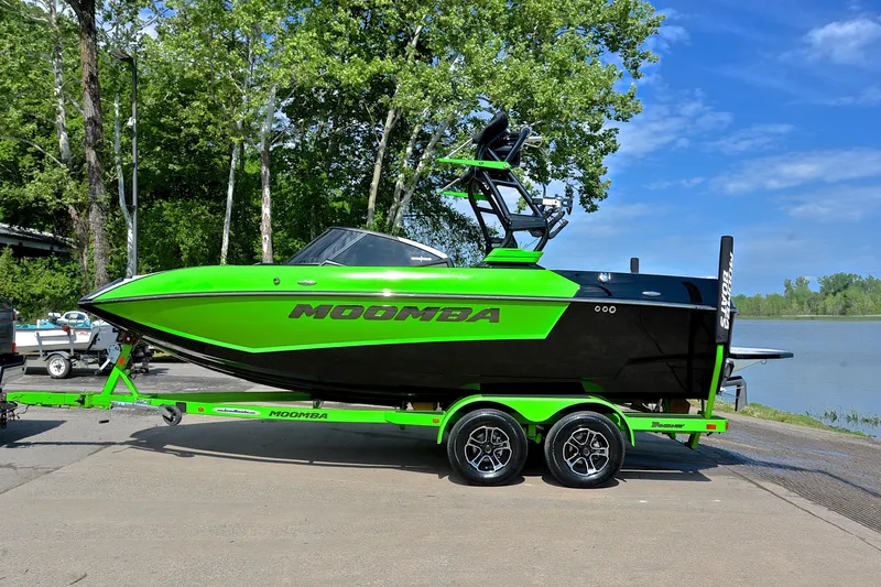 Slide: The Image of 2024 Moomba Mondo boat in vibrant green and black, parked near a lake. - 11