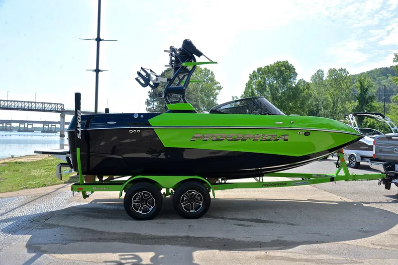 Slide: The Image of 2024 Moomba Mondo boat in vibrant green and black on a trailer by a lakeside. - 15