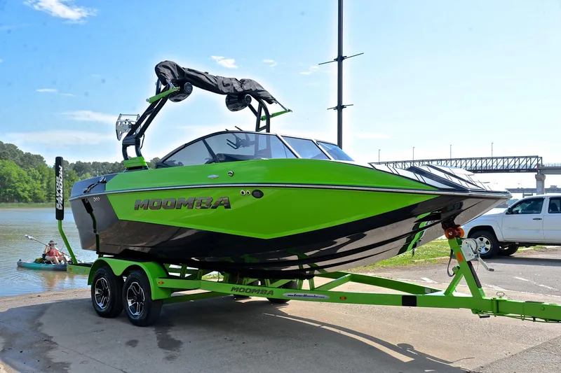 Slide: The Image of 2024 Moomba Mondo boat in vibrant green on trailer by a lakeside. - 16