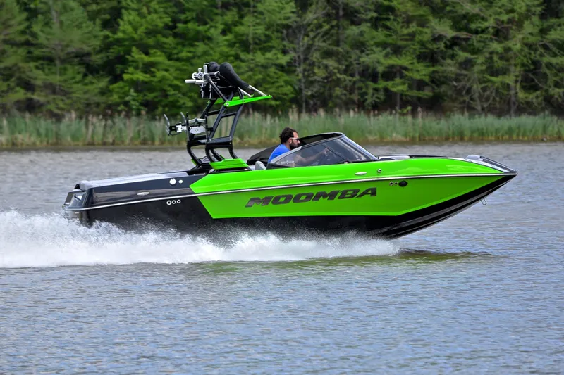 Slide: The Image of 2024 Moomba Mondo boat speeding on a lake with lush green trees in the background. - 3