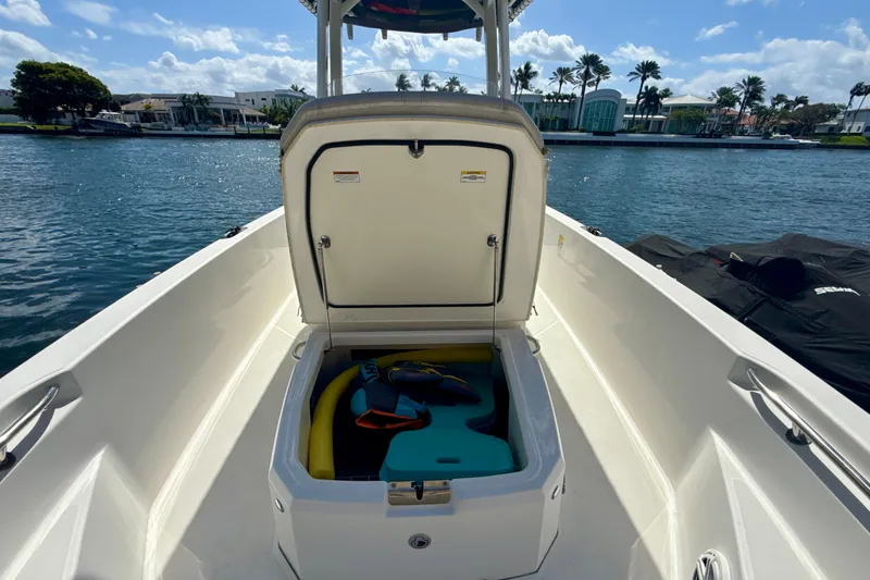 Slide: The Image of 2023 Boston Whaler 220 Dauntless boat with open storage compartment on a sunny day. - 15