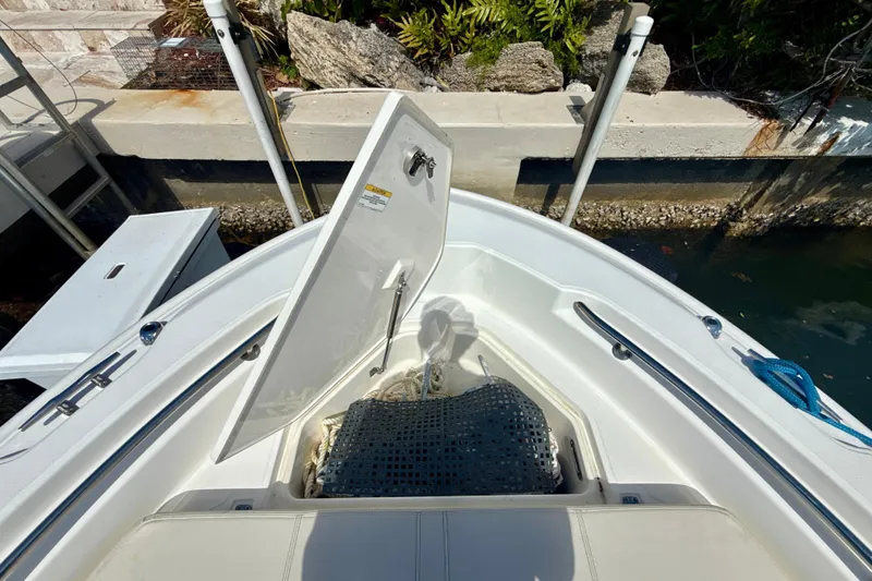 Slide: The Image of 2023 Boston Whaler 220 Dauntless boat with open storage compartment near dock. - 18