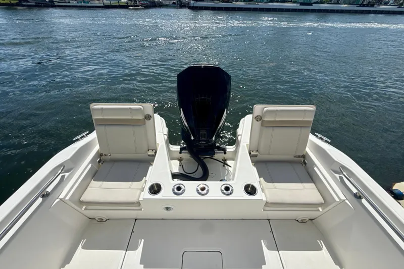 Slide: The Image of 2023 Boston Whaler 220 Dauntless boat interior with seating and motor, on calm water. - 6