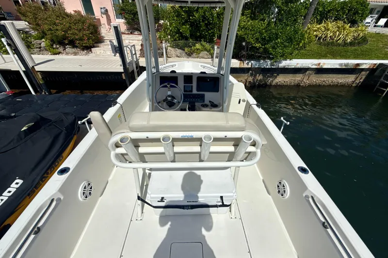 Slide: The Image of 2023 Boston Whaler 220 Dauntless boat interior with helm and seating, docked by water. - 7