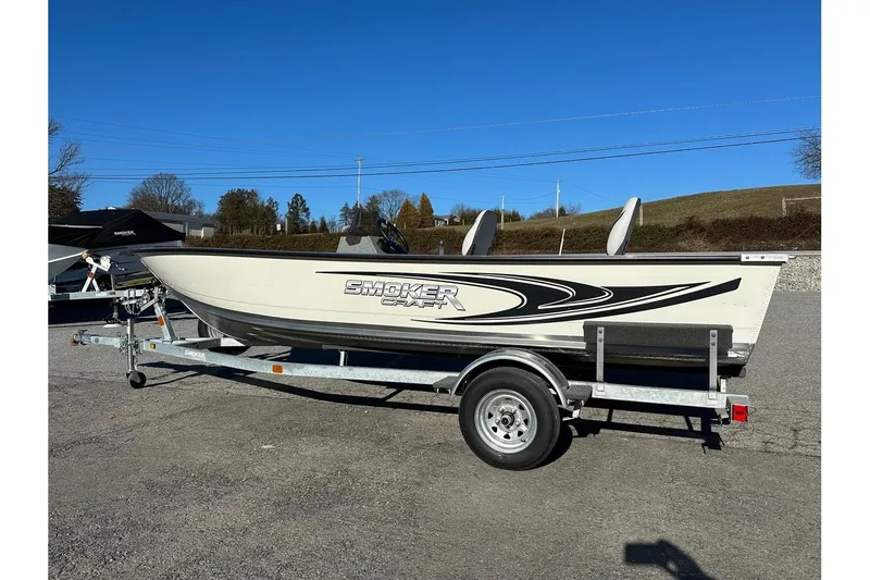 The Image of 2026 Smoker Craft Angler 16 SC boat on trailer, parked outdoors under clear blue sky. - 0