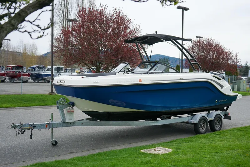 The Image of 2020 Bayliner DX 2200 boat on trailer, parked outdoors with trees in background. - 1