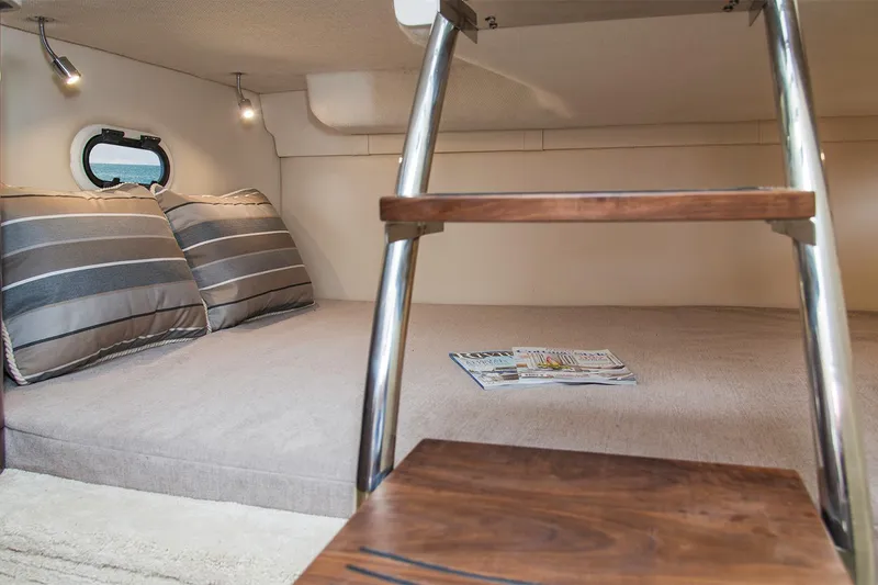 Slide: The Image of Manufacturer Provided Image: 2025 Regal 26 Express cabin interior with cozy bed, striped pillows, and wooden ladder. - 13