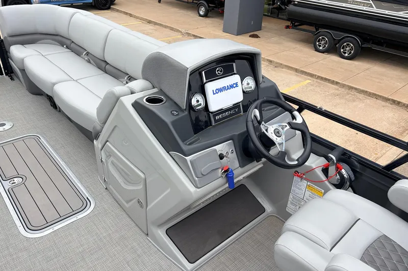 Slide: The Image of 2022 Regency 250 DL3 pontoon boat interior with steering console and plush seating. - 31