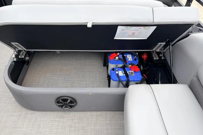 Slide: The Image of Open storage compartment in 2022 Regency 250 DL3 boat, revealing dual blue batteries. - 47