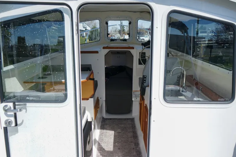 Slide: The Image of 2024 C-Dory 23' Venture Sport boat interior with seating, table, and steering area. - 11