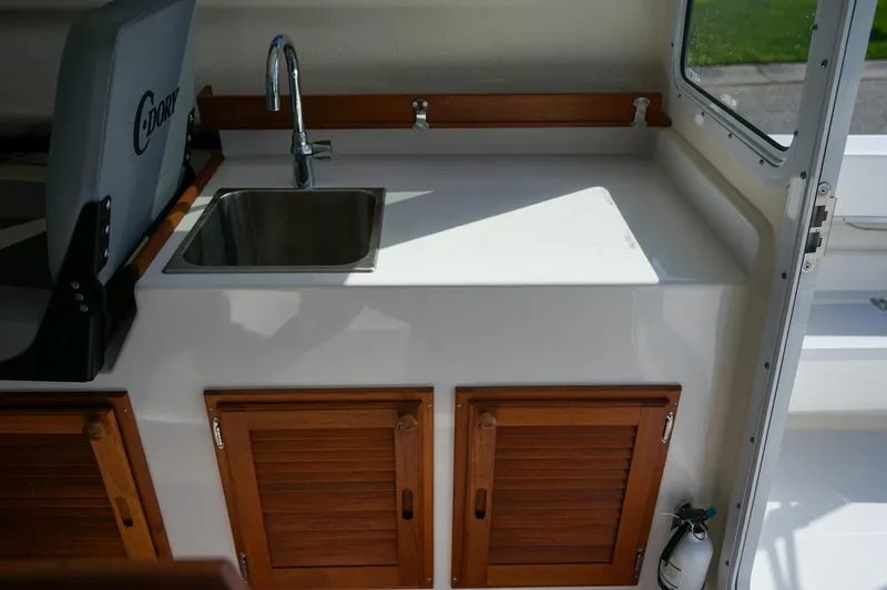 Slide: The Image of 2024 C-Dory 23' Venture Sport interior with sink and wooden cabinets. - 12