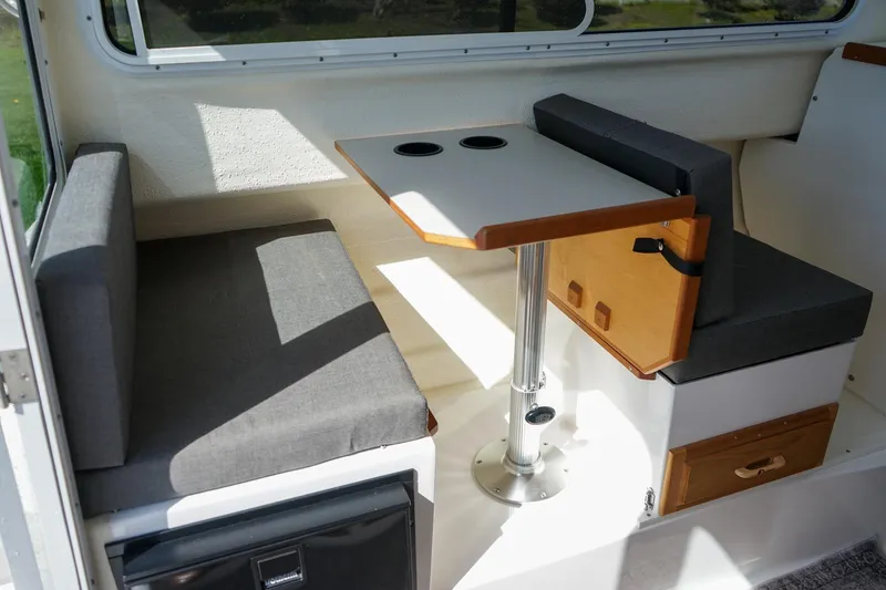 Slide: The Image of 2024 C-Dory 23' Venture Sport interior with seating and table setup. - 15