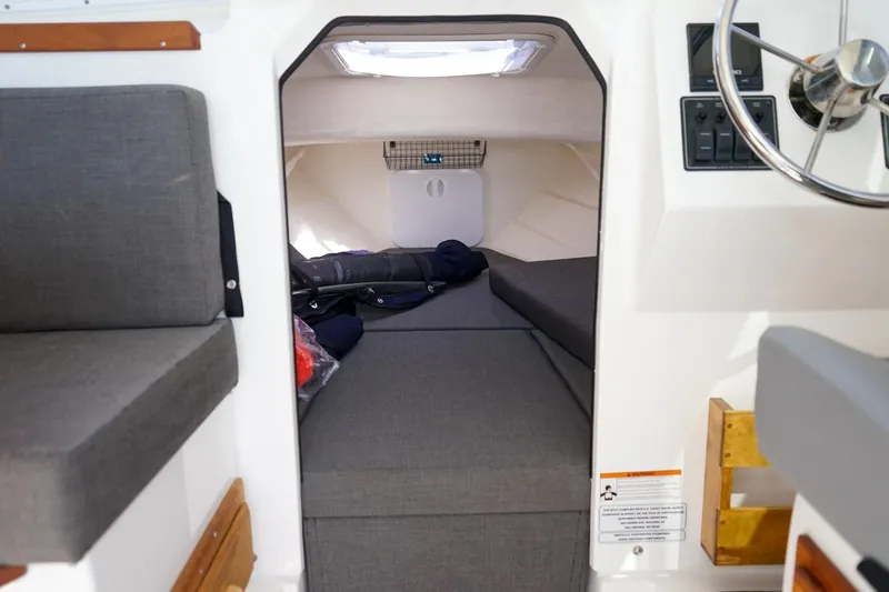 Slide: The Image of 2024 C-Dory 23' Venture Sport cabin interior with gray seating and steering wheel. - 18